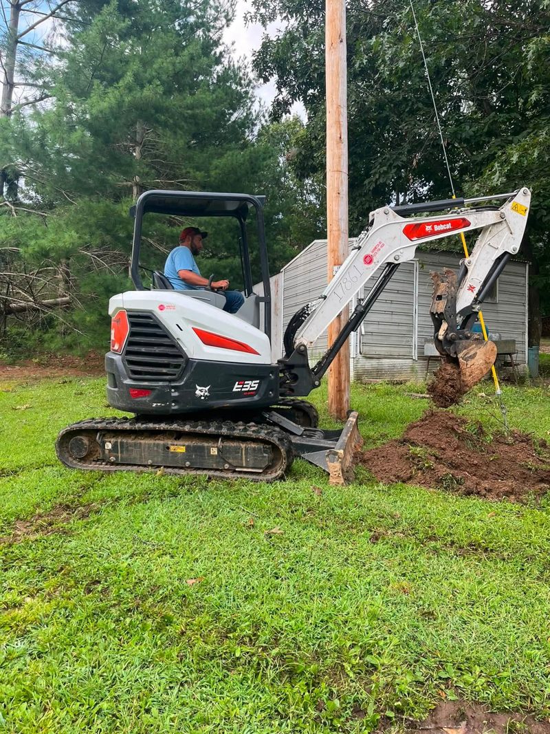 A Bobcat E35 mini excavator trenching a waterline beside a utility pole