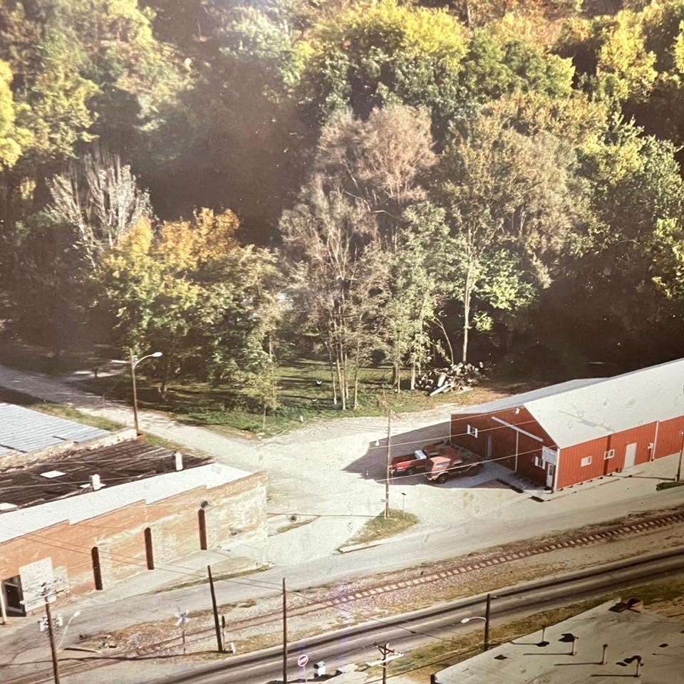 An old aerial photograph of the Lead Belt Pump & Supply shop, a red metal building beside the railroad tracks with a red truck out front
